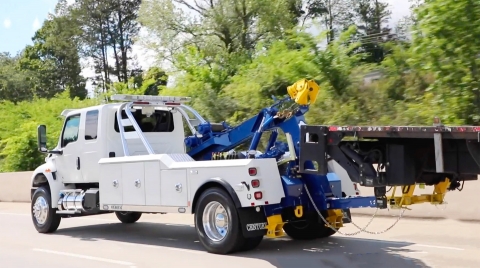 Century 3212 towing a flat bed truck from the rear.