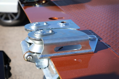 Side view of a Miller Industries approach plate roller guide attachment installed on a rollback.