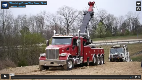 This photos shows a Century 1150 rotator winching a loaded trash truck up from the side of a hill while it is recovered from mud.