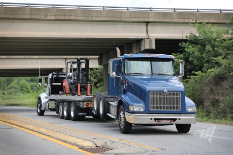 Century 20-series industrial carrier hauling a forklift while also towing a road tractor truck.