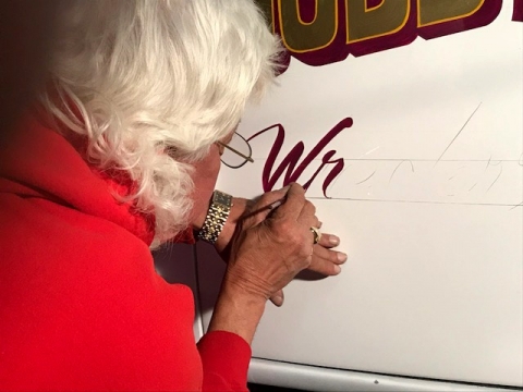 Vance Dobbins hand lettering the door panel of the Holmes 330 Junior known as Sally